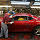 A red Chevrolet Camaro being detailed on an assembly line